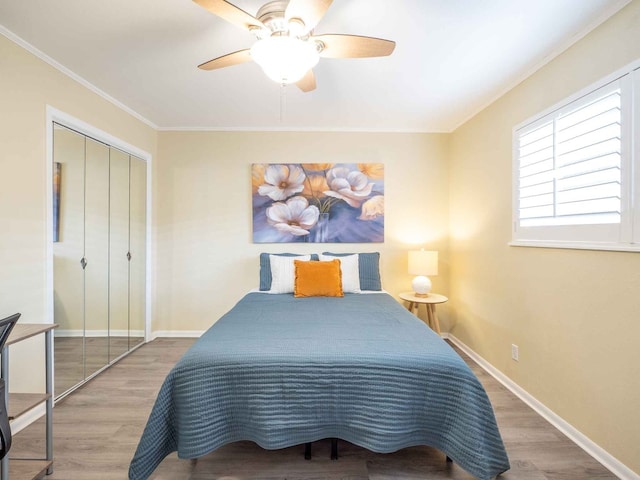 bedroom with a closet, ceiling fan, wood-type flooring, and ornamental molding