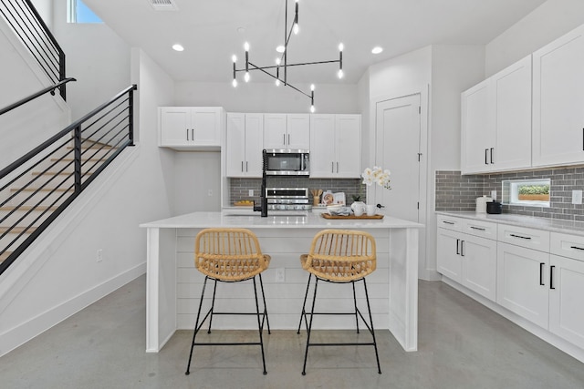 kitchen with light countertops, stainless steel microwave, range, and finished concrete flooring