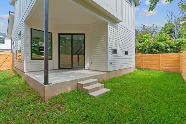 back of house with board and batten siding, a patio area, a yard, and a fenced backyard