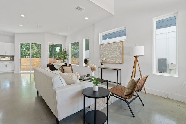 living room featuring baseboards, finished concrete floors, visible vents, and recessed lighting