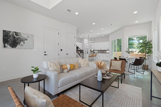 living room featuring a chandelier and concrete flooring