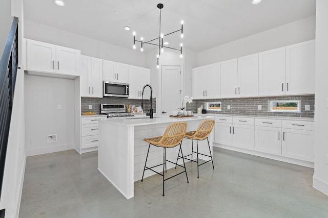 kitchen with appliances with stainless steel finishes, finished concrete floors, white cabinetry, and a sink