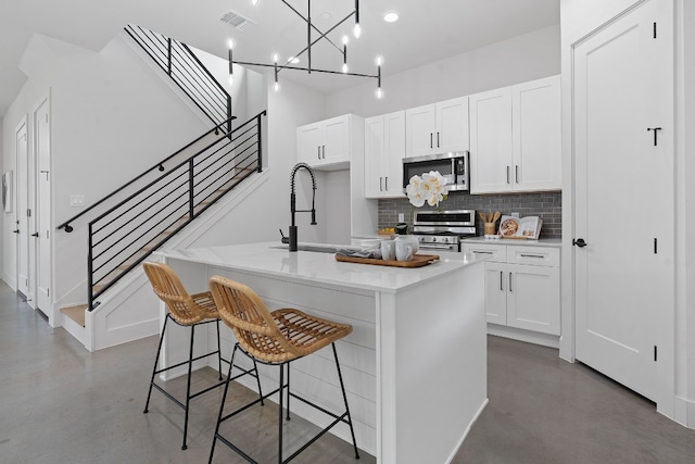 kitchen with stainless steel appliances, visible vents, a sink, and finished concrete flooring