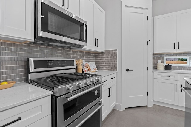 kitchen with concrete flooring, stainless steel appliances, white cabinetry, decorative backsplash, and light stone countertops