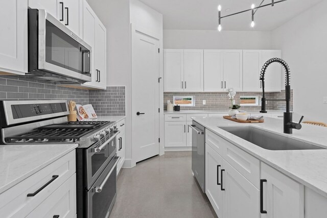 kitchen featuring backsplash, white cabinetry, stainless steel appliances, and a sink