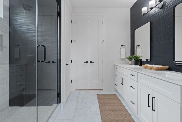 bathroom with marble finish floor, double vanity, a stall shower, and a sink