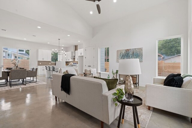 living room with ceiling fan with notable chandelier and high vaulted ceiling