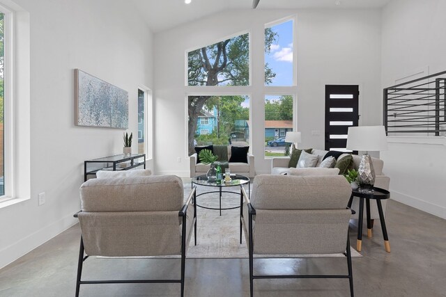 living room with a wealth of natural light, concrete floors, and high vaulted ceiling