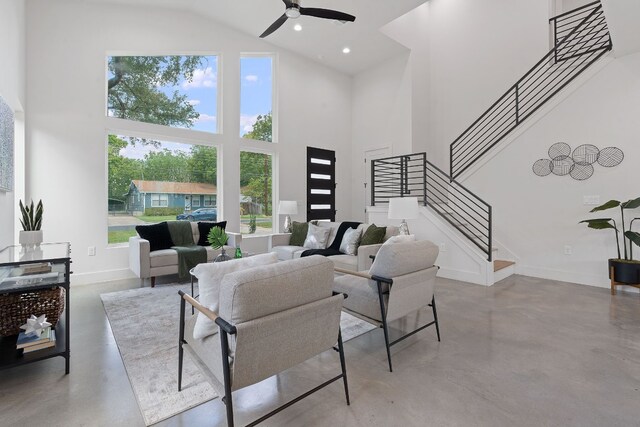 living room featuring a towering ceiling, concrete flooring, and ceiling fan