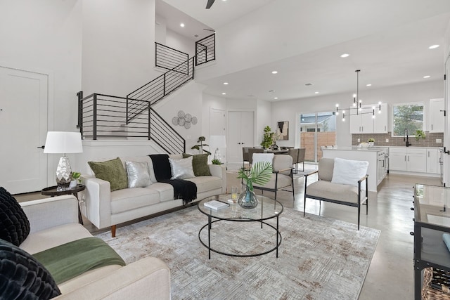 living room with a towering ceiling, sink, and a notable chandelier