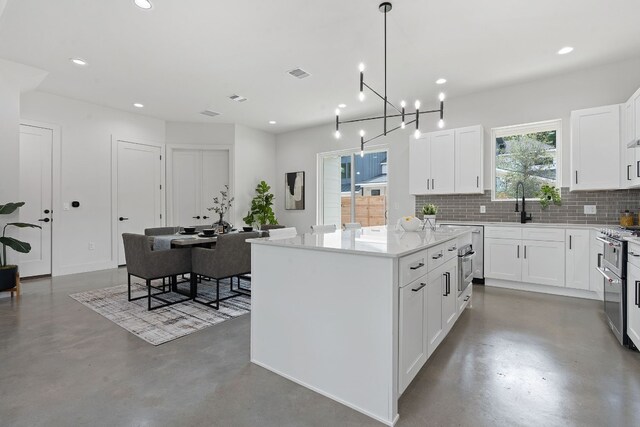 kitchen with light stone counters, a chandelier, white cabinetry, a kitchen island, and tasteful backsplash