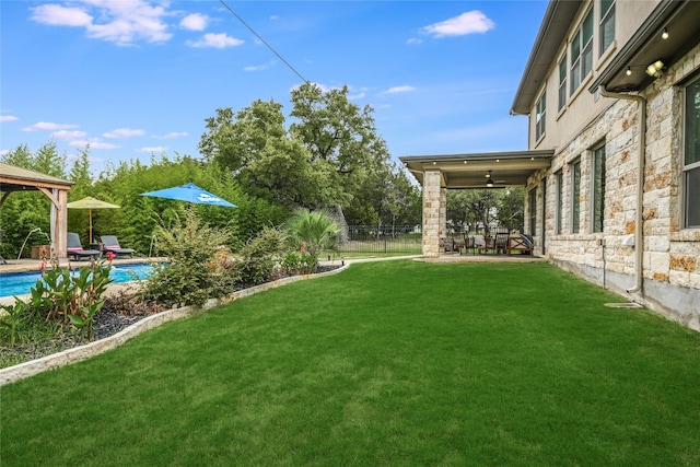 view of yard with ceiling fan, fence, an outdoor pool, and a gazebo