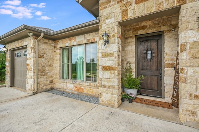 doorway to property with a garage and stone siding