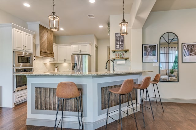 kitchen featuring white cabinetry, appliances with stainless steel finishes, light stone counters, and decorative light fixtures