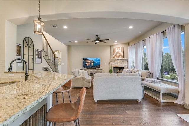 living area featuring visible vents, dark wood finished floors, stairs, a stone fireplace, and recessed lighting