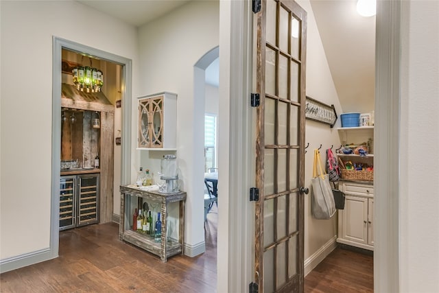 hall featuring arched walkways, dark wood-style flooring, beverage cooler, and baseboards