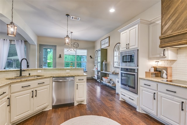 kitchen with decorative light fixtures, stainless steel appliances, visible vents, white cabinetry, and a sink