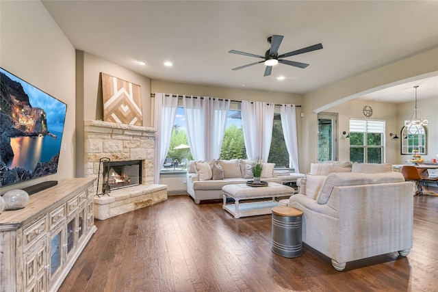 living room featuring plenty of natural light, dark hardwood / wood-style floors, and a stone fireplace