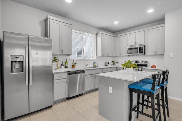 kitchen featuring appliances with stainless steel finishes, a center island, light tile patterned flooring, and sink