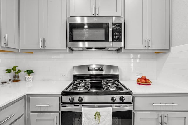 kitchen featuring backsplash, stainless steel appliances, and gray cabinetry