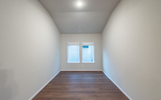 unfurnished room featuring lofted ceiling and dark hardwood / wood-style floors