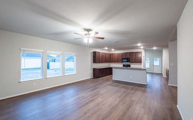 kitchen featuring black appliances, a textured ceiling, a center island, ceiling fan, and dark hardwood / wood-style floors