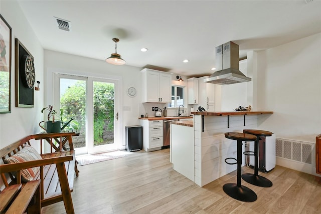 kitchen with dishwasher, kitchen peninsula, island exhaust hood, pendant lighting, and white cabinets