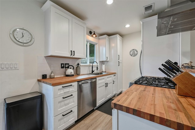 kitchen featuring wood counters, white cabinetry, stainless steel dishwasher, and sink