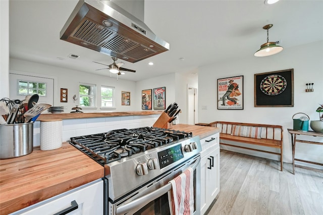 kitchen featuring wooden counters, ventilation hood, white cabinets, stainless steel range, and decorative light fixtures