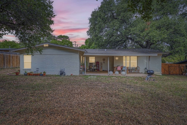 back house at dusk with a yard and a patio