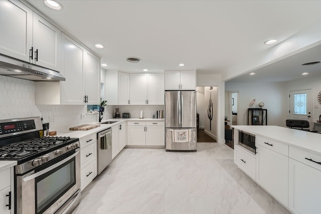 kitchen with appliances with stainless steel finishes, white cabinetry, backsplash, and sink