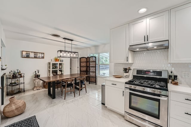 kitchen featuring pendant lighting, decorative backsplash, stainless steel gas stove, and white cabinetry