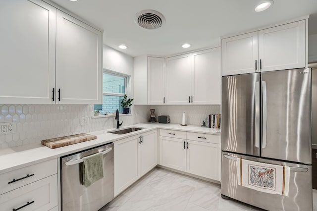 kitchen with appliances with stainless steel finishes, sink, white cabinets, and decorative backsplash