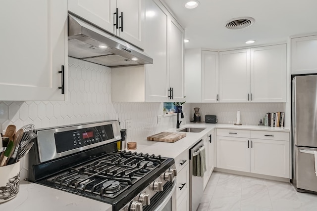 kitchen with appliances with stainless steel finishes, tasteful backsplash, sink, and white cabinets