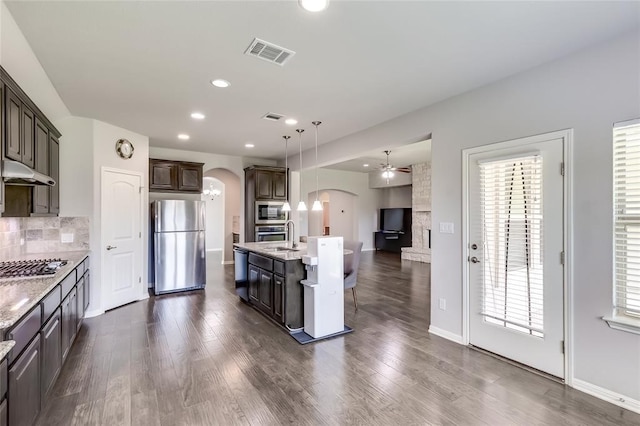 kitchen featuring dark brown cabinetry, stainless steel appliances, a kitchen island with sink, decorative light fixtures, and dark hardwood / wood-style floors