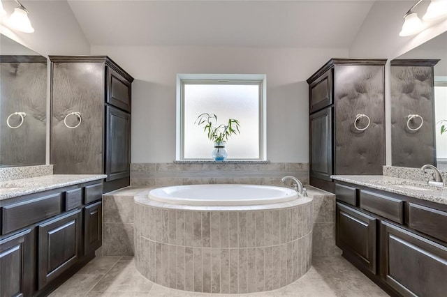 bathroom with vanity, tile patterned flooring, a relaxing tiled tub, and lofted ceiling