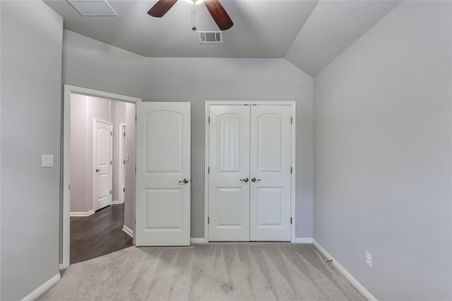 unfurnished bedroom featuring ceiling fan, a closet, light carpet, and lofted ceiling