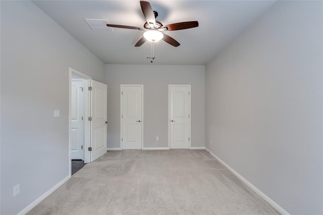 unfurnished bedroom with multiple closets, ceiling fan, and light colored carpet