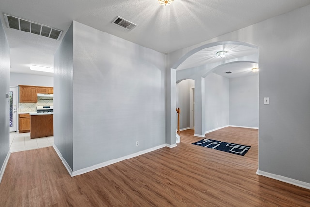 empty room with a textured ceiling and light wood-type flooring