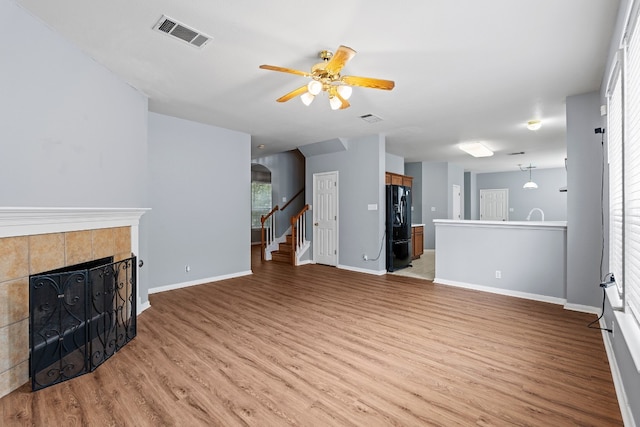 living room with a fireplace, light hardwood / wood-style flooring, and ceiling fan