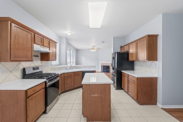 kitchen with a center island, stainless steel gas range oven, ceiling fan, light tile patterned floors, and tasteful backsplash