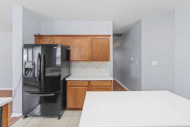 kitchen with backsplash, black fridge, and light tile patterned floors