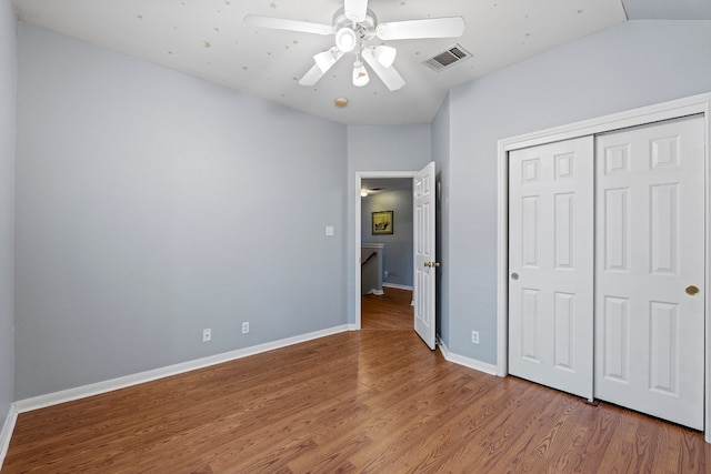 unfurnished bedroom featuring ceiling fan, a closet, wood-type flooring, and lofted ceiling