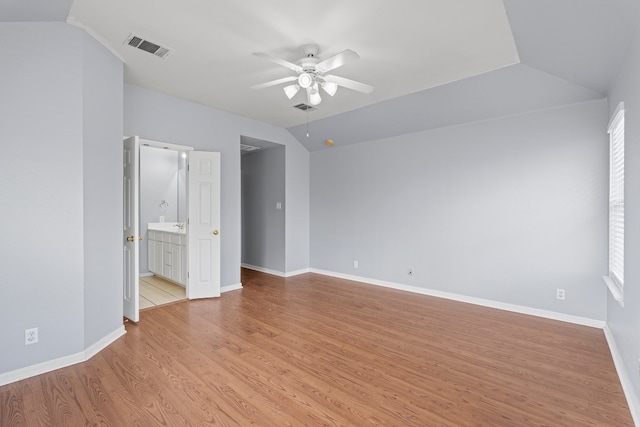 unfurnished bedroom with ceiling fan, light wood-type flooring, connected bathroom, and lofted ceiling