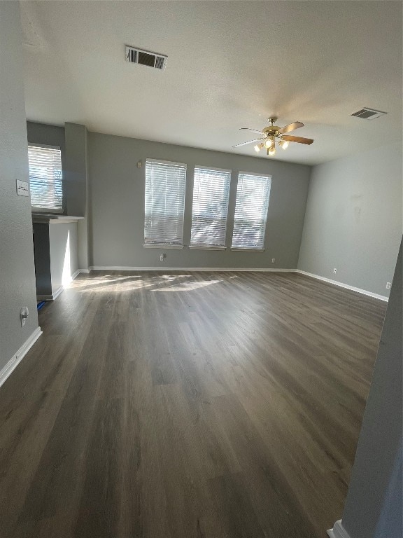 spare room with a textured ceiling, dark hardwood / wood-style floors, plenty of natural light, and ceiling fan