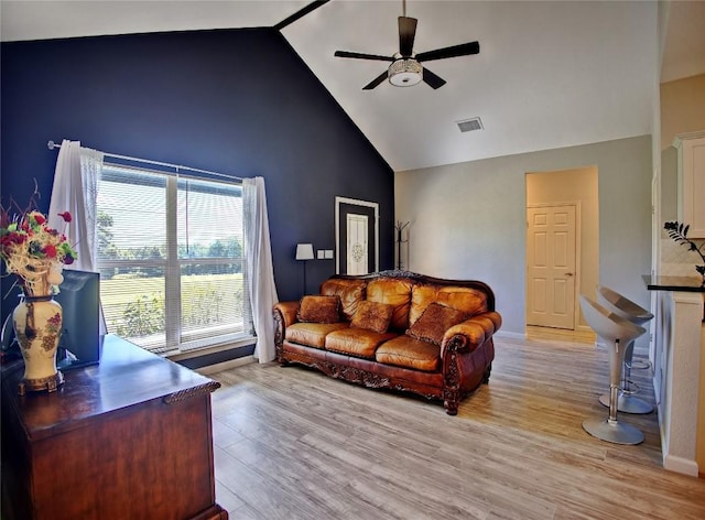 living area featuring visible vents, baseboards, high vaulted ceiling, a ceiling fan, and light wood finished floors