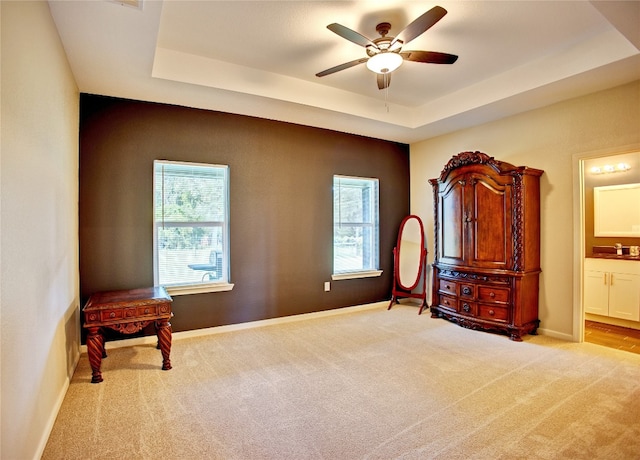 interior space with a raised ceiling, ceiling fan, sink, and light carpet