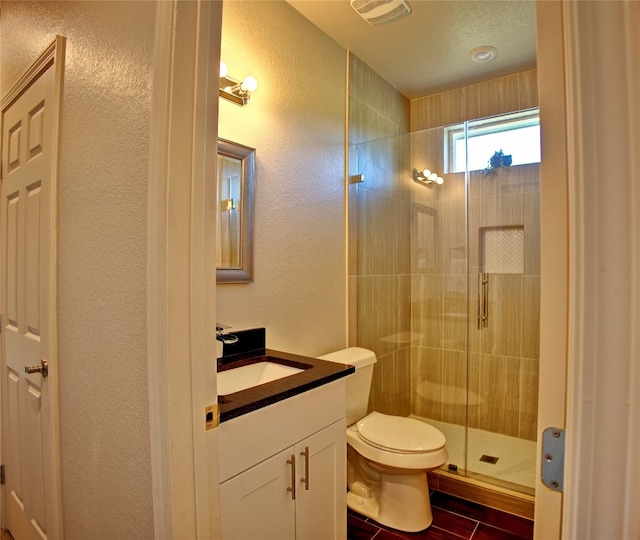 bathroom featuring a shower with door, vanity, a textured ceiling, wood-type flooring, and toilet