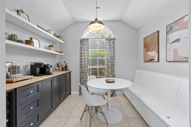 tiled dining space featuring vaulted ceiling