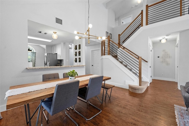 dining room with an inviting chandelier, a high ceiling, and dark hardwood / wood-style floors